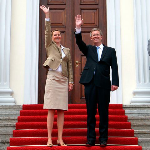 Bettina und Christian Wulff stehen auf einer Treppe und winken