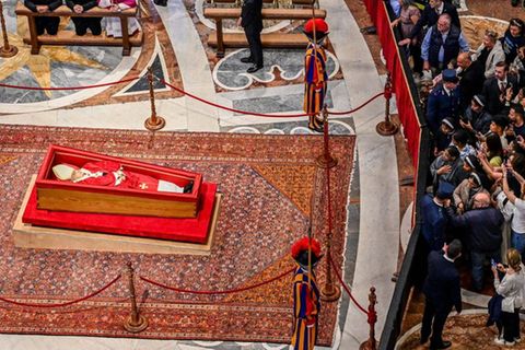 Eine Menschentraube steht vor dem aufgebahrten Papst Franziskus, manche machen Fotos