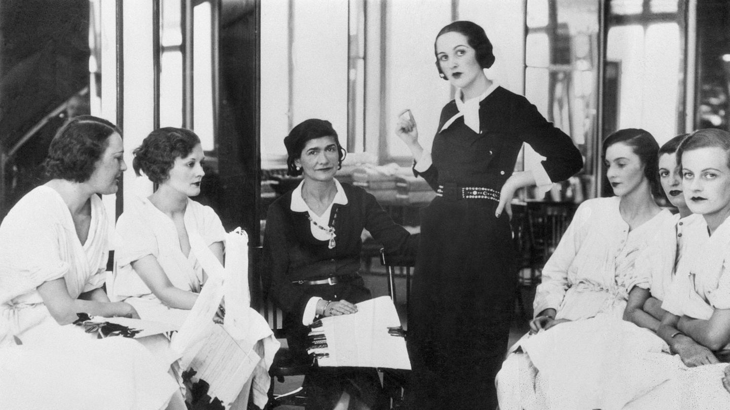 Cooc Chanel sitzt umrahmt voin ihren Kundinnen im Salon von Chanel in Paris