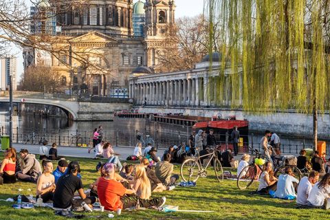 Menschen entspannen sich auf einer Wiese mit Blick auf Museumsinsel und Berliner Dom