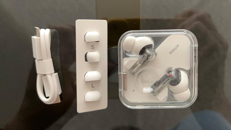 Ladecase, Ladekabel und Gelpads liegen auf einem Glastisch Ladecase, Ladekabel und Gelpads liegen auf einem Glastisch