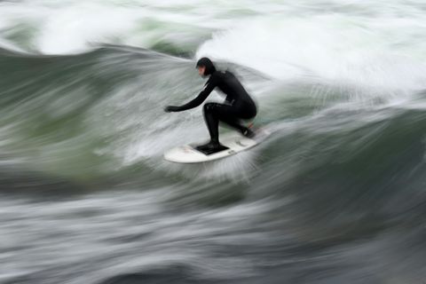 Ein Surfer auf der Eisbachwelle in München
