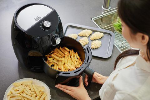 Eine Frau frittiert Pommes in einem Airfryer