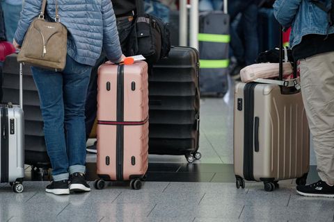 Reisende stehen mit ihrem Gepäck an einem Flughafen