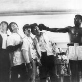 Ali streckt die Faust nach den Beatles aus, die links von ihm aufgereiht stehen