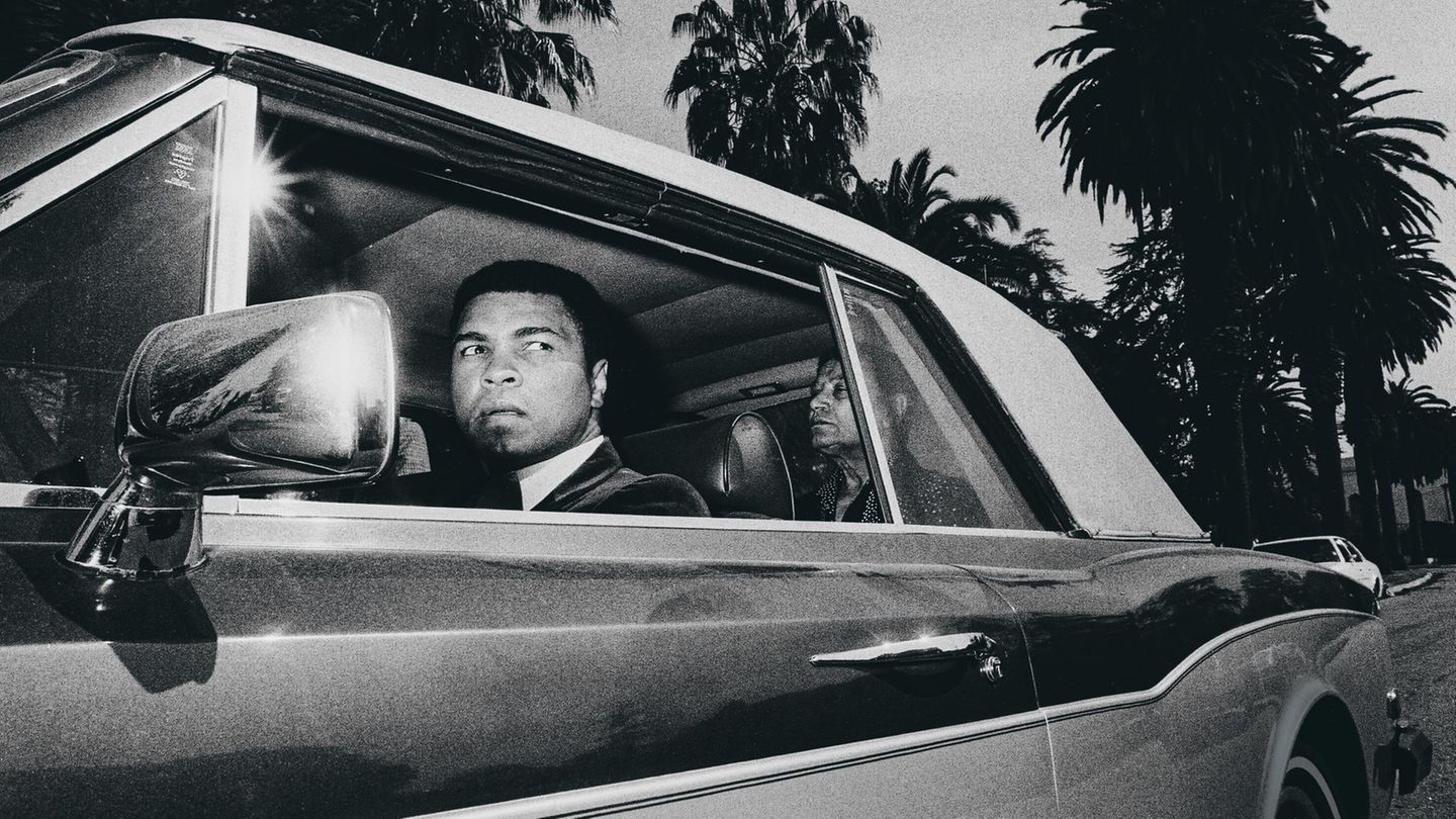Ali im Rolls-Royce, er schaut aus dem Fahrerfenster. Sein marokkanischer Butler sitzt auf dem Rücksitz.