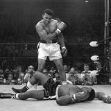 Ali nach gewonnenem Kampf gegen Sonny Liston, der am Boden liegt: Ali ballt die Faust und schaut auf ihn runter