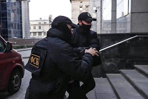 Zwei vermummte FSB-Agenten führen einen Verdächtigen ab