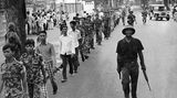 Südvietnamesische Soldaten werden von nordvietnamesischen Soldaten auf einer Straße von Saigon eskortiert