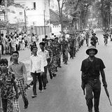 Südvietnamesische Soldaten werden von nordvietnamesischen Soldaten auf einer Straße von Saigon eskortiert