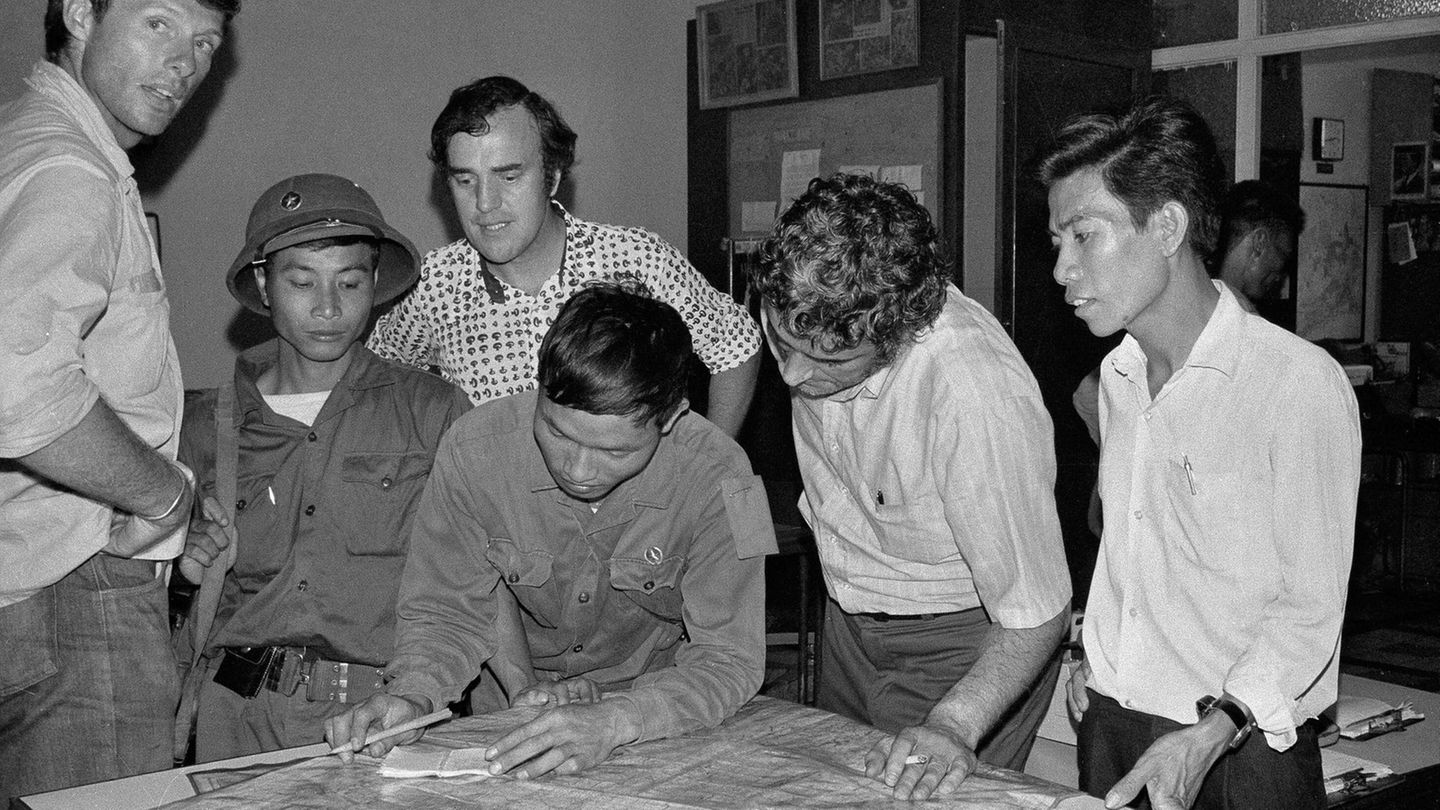 Drei US-Journalisten im Büro der AP mit zwei nordvietnamesischen Soldaten beugen sich über Landkarte