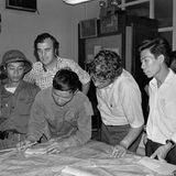 Drei US-Journalisten im Büro der AP mit zwei nordvietnamesischen Soldaten beugen sich über Landkarte