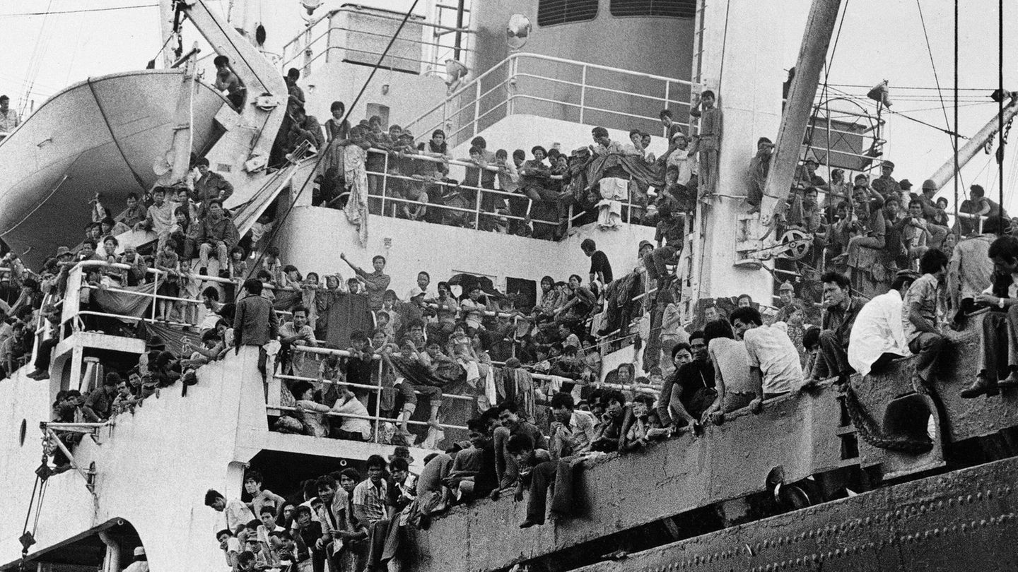 Überdimensionierte Rettungsboote Ein Schiff voller Menschen, die teilweise auf der Reling sitzen