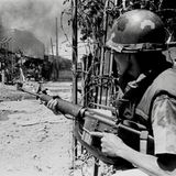 Soldat versteckt sich hinter einer Wand und schaut auf eine verwüstete Straße