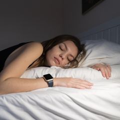 Young woman sleeping with smart watch tracker at night