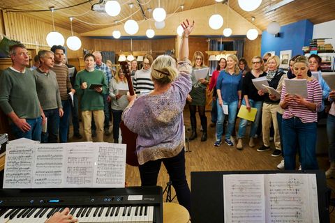 Eine Frau gibt den Ton für einen Chor an - ein Bild für Zusammenhalt in schweren Zeiten
