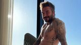 David Beckham, lange Schlafanzughose, nackter Oberkörper, sitzt in seinem Apartment in Miami vor einem Fenster