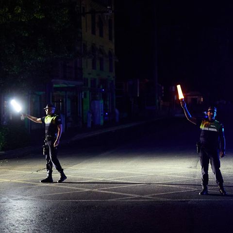 Zwei Polizisten auf der Straße halten während des Blackouts Lampen in der Hand – um sie rum ist alles finster