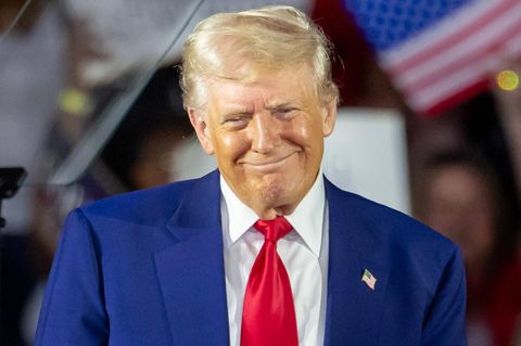Donald Trump grinst schelmisch auf der Bühne zu einer "Präsidentenfeier"