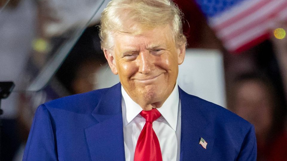 Donald Trump grinst schelmisch auf der Bühne zu einer "Präsidentenfeier"