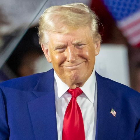 Donald Trump grinst schelmisch auf der Bühne zu einer "Präsidentenfeier"