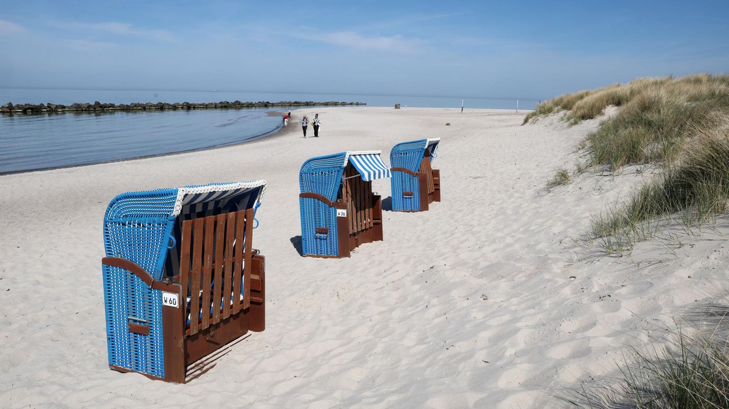 Drei blaue Strandkörbe stehen bei schönstem Wetter am Rand einer Düne
