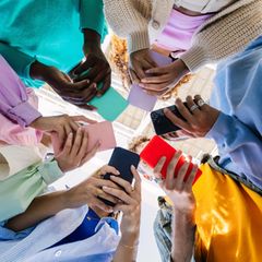 Günstiges Smartphone. Junge Menschen stehen im Kreis und schauen Ihre Handys
