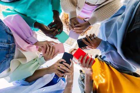 Günstiges Smartphone. Junge Menschen stehen im Kreis und schauen Ihre Handys