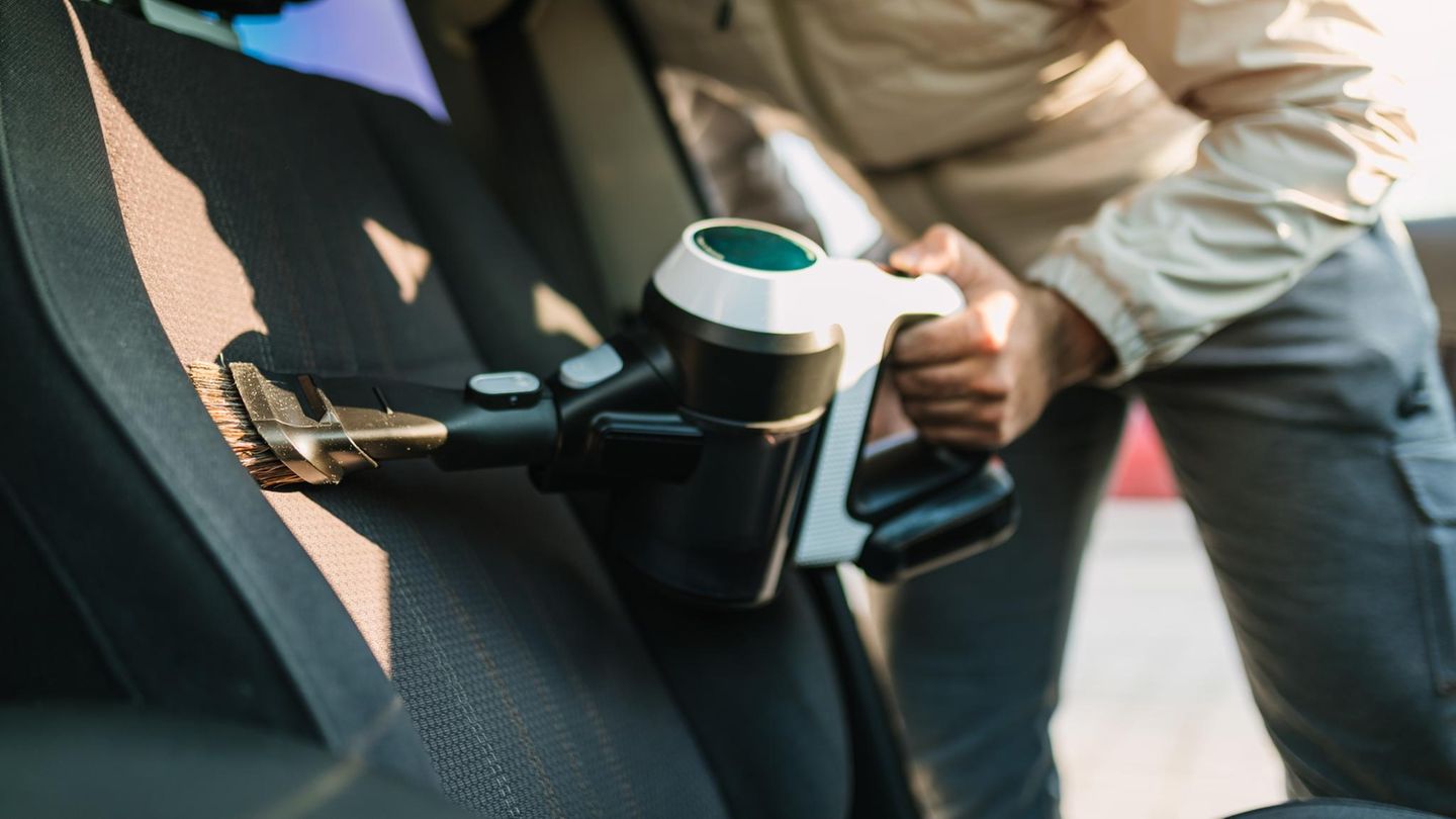 Man Using Portable Vacuum Cleaner to Clean Interior of Vehicle Seat