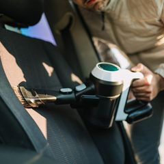 Man Using Portable Vacuum Cleaner to Clean Interior of Vehicle Seat