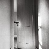 Eine Hand fasst einen Türknopf und ihr Schatten ebenso