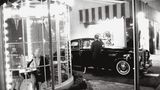 Blick in ein rundes Café, hinter dem eine Frau aus einem Rolls-Royce steigt