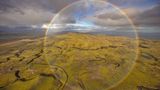Magisches Portal über Island? In 300 Meter Höhe gelang es Peter Schwager, ein besonderes Naturschauspiel festzuhalten: Aus einem Hubschrauber ohne Türen heraus knipste er den runden Regenbogen über den Weiten der isländischen Natur. 