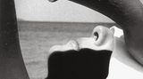 Eine Frau liegt am Meer und hält sich ein weißes Tuch über die Augen