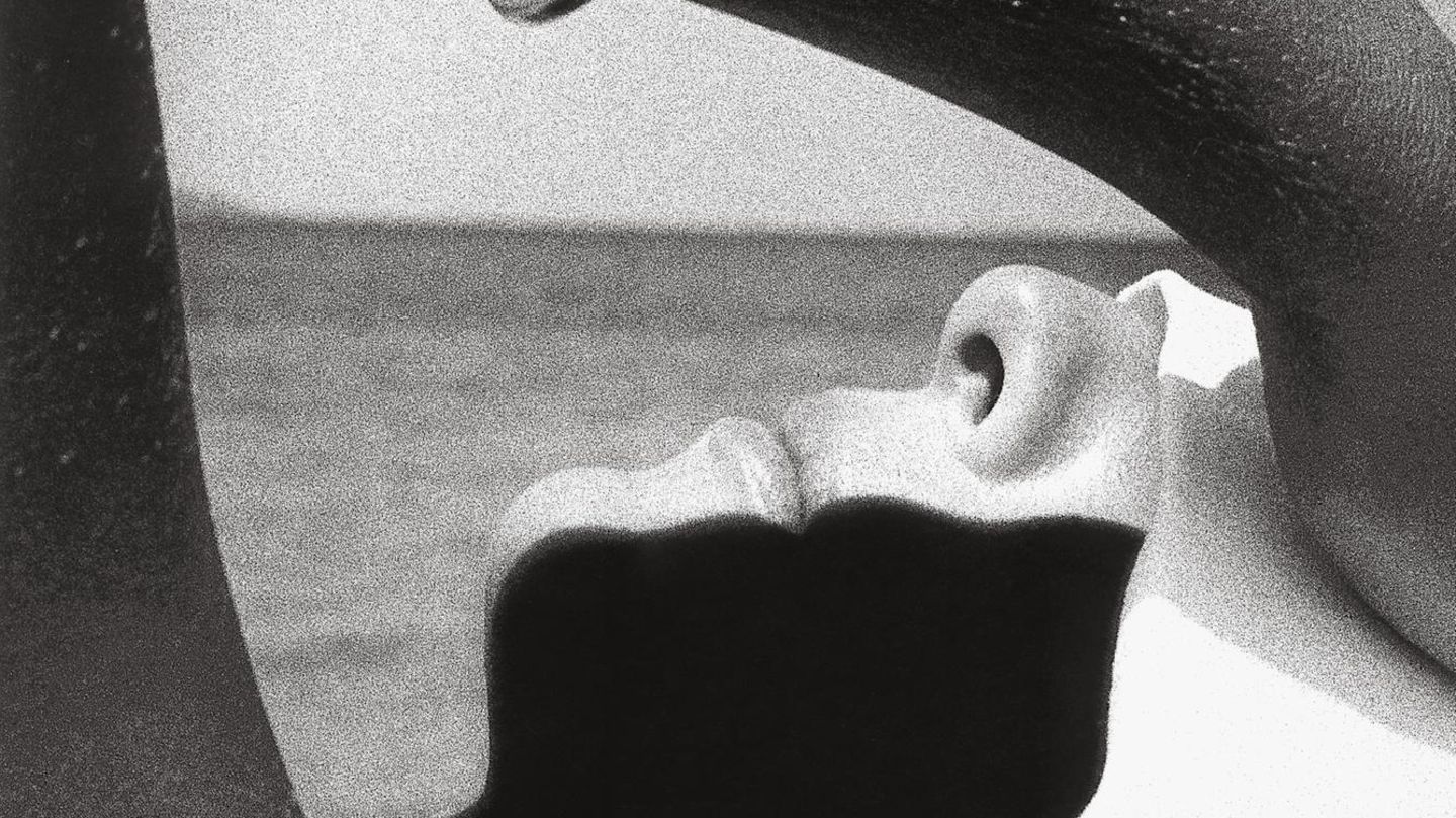 Eine Frau liegt am Meer und hält sich ein weißes Tuch über die Augen