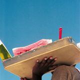 Eine schwarze Hand trägt ein Tablett mit geschnittener Wassermelone