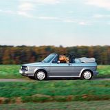VW Golf  Für die einen war er der absolute Traumwagen, für andere ein Objekt des Spotts: das viersitzige Golf Cabrio der Einstiegsklasse, das 1979 mit seinem charakteristischen Überrollbügel das technisch veraltete VW Käfer Cabrio ablöste. Zugegeben, eine Schönheit war der Überrollbügel, der das Golf Cabrio zum "Erdbeerkörbchen" oder "Henkelmann" machte, nicht. Doch die wenig filigrane Überschlagslösung war in den 1980er-Jahren die einzige bezahlbare Möglichkeit, neuen Sicherheitsanforderungen zu genügen. Die direkten Wettbewerber Opel Kadett und Ford Escort zogen nach und trugen bei schönem Wetter ihren schwarzen "Henkelmann" zur Schau, der sich sonst unter der stramm sitzenden Mütze verbarg