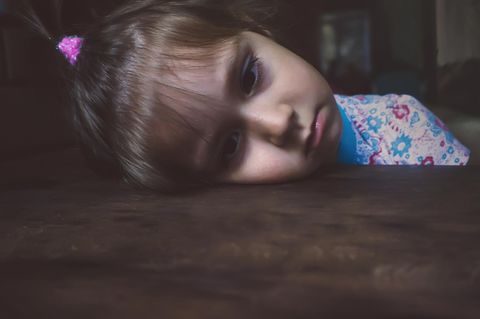 Kinder: Ein kleines Mädchen legt traurig ihren Kopf auf den Tisch