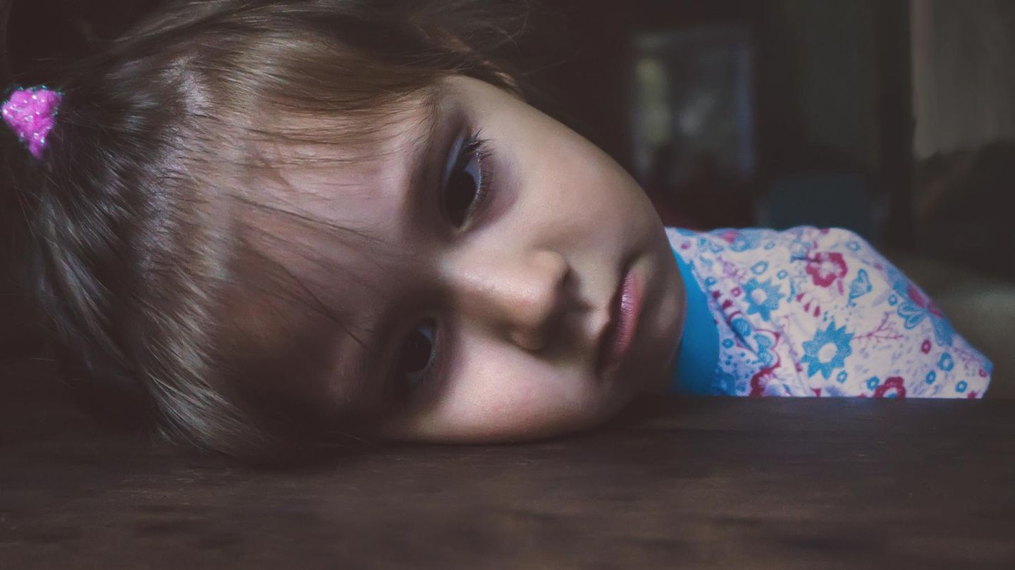 Kinder: Ein kleines Mädchen legt traurig ihren Kopf auf den Tisch