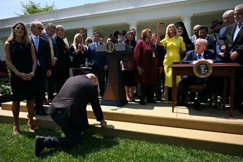 Ein Mann kniet betend vor Trump nieder