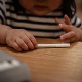 Ein Kleinkind greift nach einer auf dem Tisch liegende Zigarette