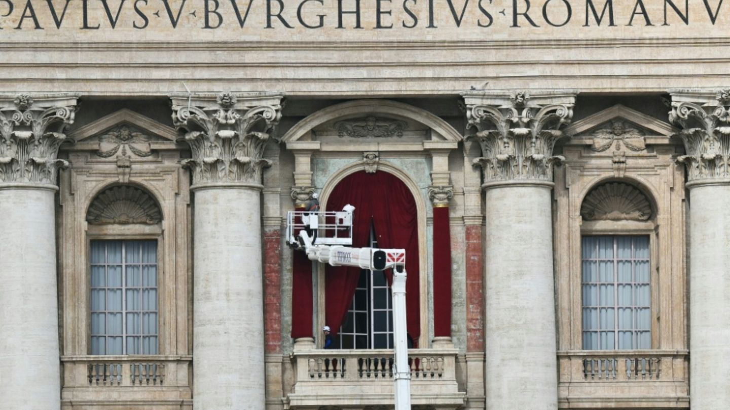 Rote Vorhänge werden am Balkon des Petersdoms angebracht