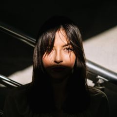 Gesicht einer jungen Frau in einem Streifen Sonnenlicht. Sie hat dunkle Haare und möglicherweise Selbstzweifel