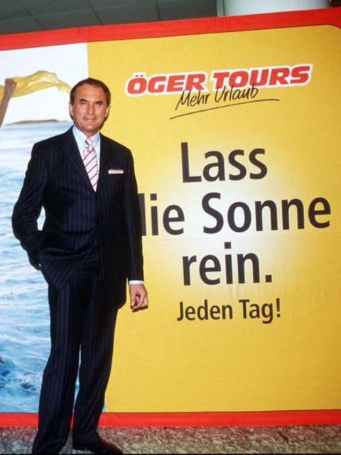Vural Öger steht vor einem Plakat seiner Firma