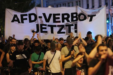 Teilnehmer einer linken Demonstration gehen mit Transparent mit der Aufschrift "AfD- Verbot jetzt!" eine Straße entlang