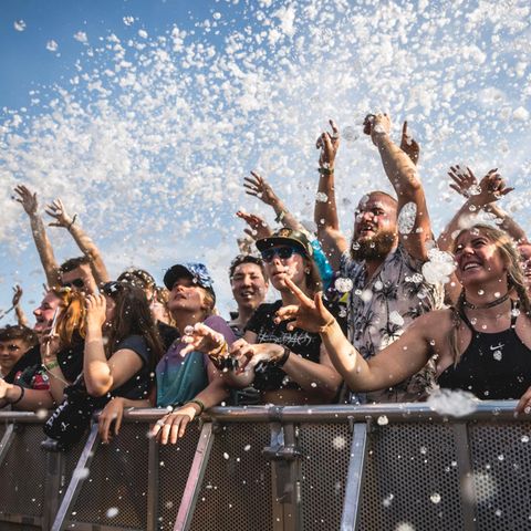 Fans celebrate the music in the front row in front of the stage at Eventims Hurricane Festival-foam hovers in the air above them