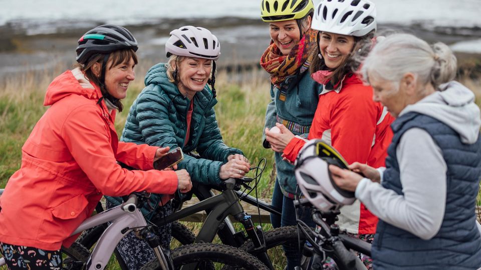 Eine Gruppe Seniorinnen mit Fahrradhelmen und E-bikes in der Natur Eine Gruppe Seniorinnen mit Fahrradhelmen und E-bikes in der Natur