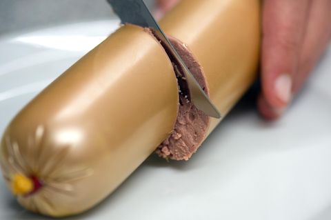 Jemand schneidet eine Leberwurst durch – gehört die Pelle zur Verpackung?