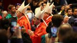 Die Geistlichen ziehen zwischen den wartenden Gläubigen in die Kirche ein