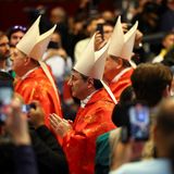 Die Geistlichen ziehen zwischen den wartenden Gläubigen in die Kirche ein